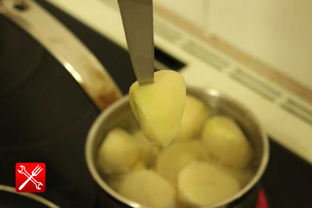 Проверка на готовность отварной картошки при помощи ножа, сырая картошина легко вытаскивается из кастрюли, а вареная соскакивает с ножа