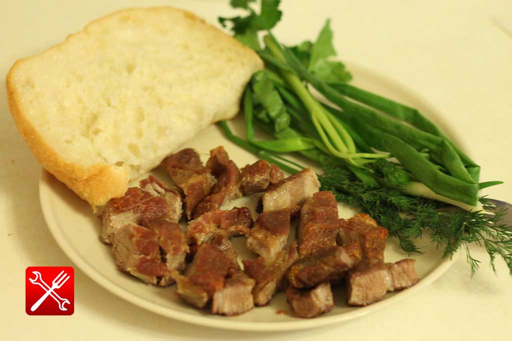 Вариант сервировки жареной свинины белым хлебом и зеленью